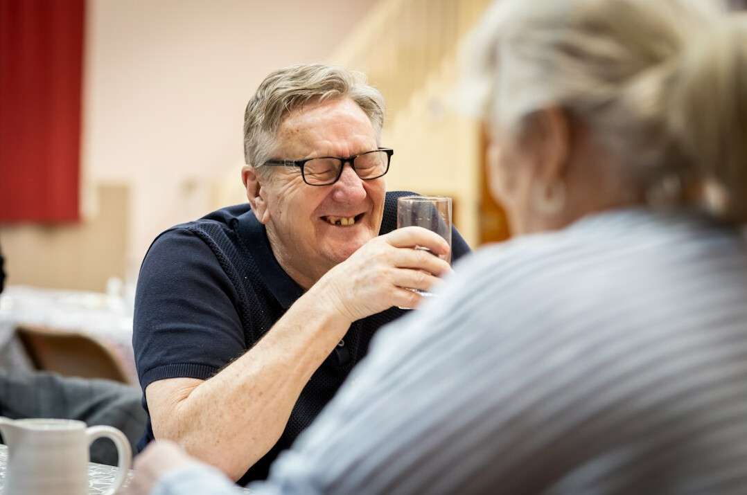 Senior woman and senior man having tea and chatting at a community club table
